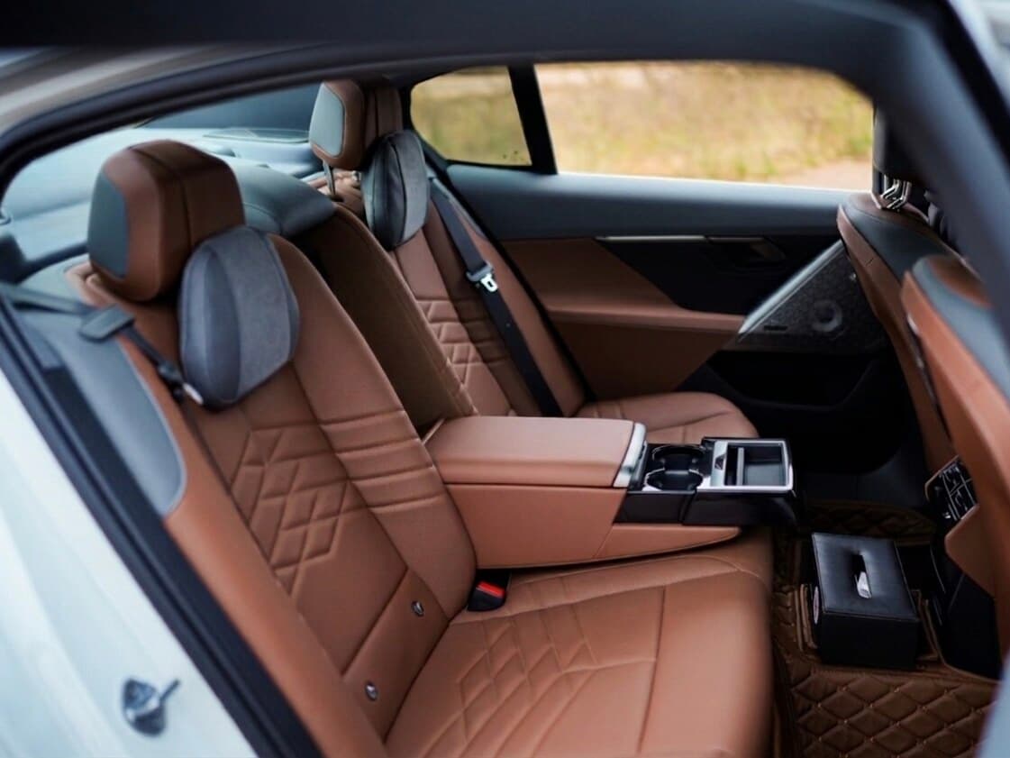 BMW 530 Li M Sport rear seat cabin with cognac diamond-quilted leather, suede headrest cushions, and rear armrest with cup holders — premium chauffeur-driven car rental in Bangalore